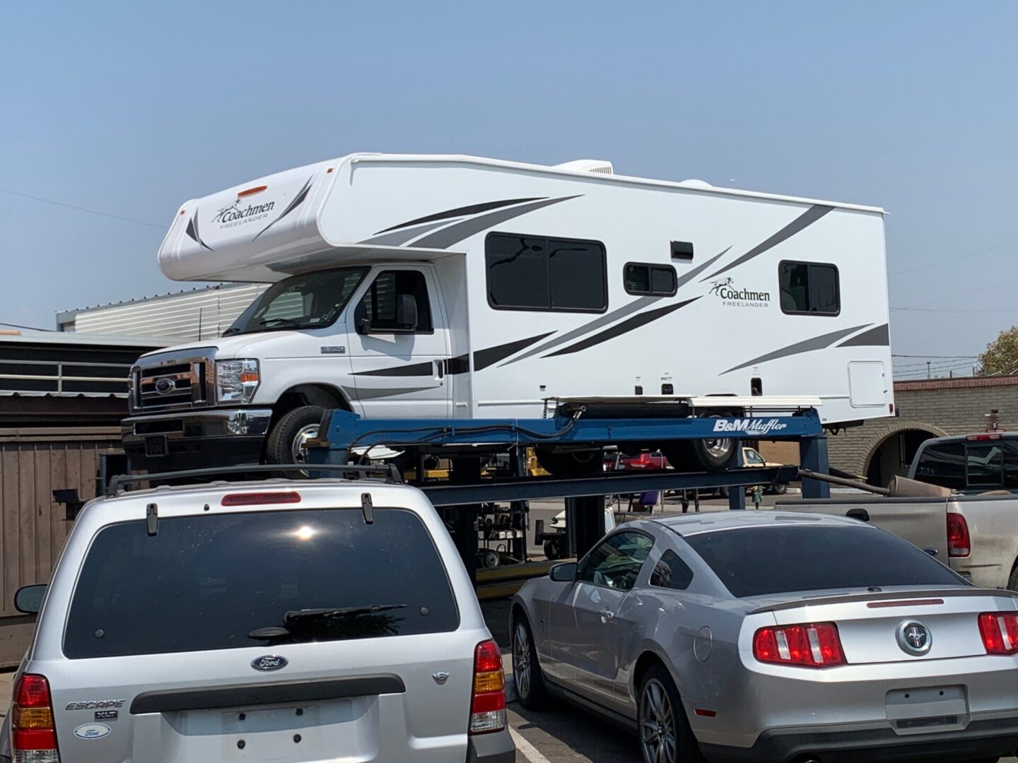 A white rv is being loaded onto the back of a truck.