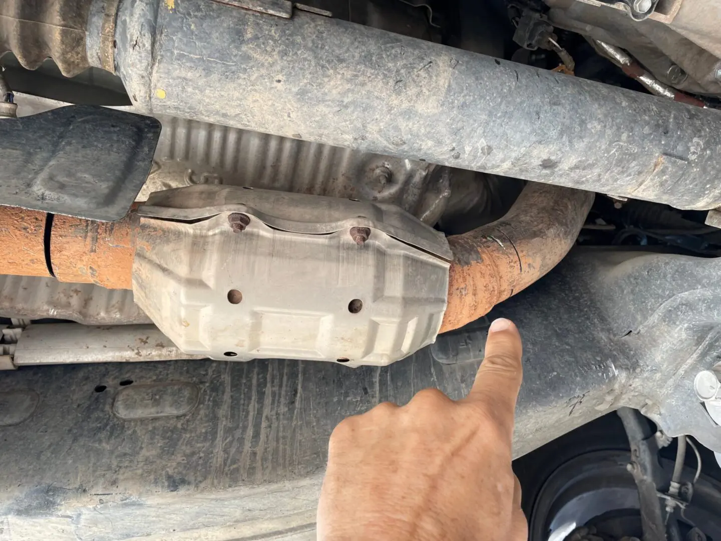 A person pointing to the exhaust pipe of an engine.